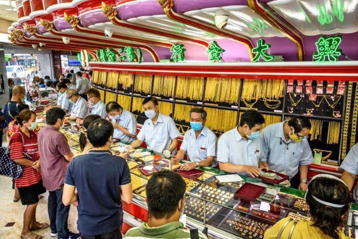 Customers in facemasks selling gold at a shop in Bangkok's Chinatown