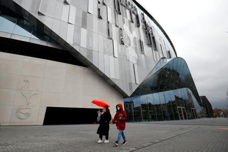 A woman wearing a protective face mask walks near the Tottenham Hotspur Stadium