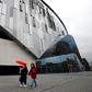 A woman wearing a protective face mask walks near the Tottenham Hotspur Stadium
