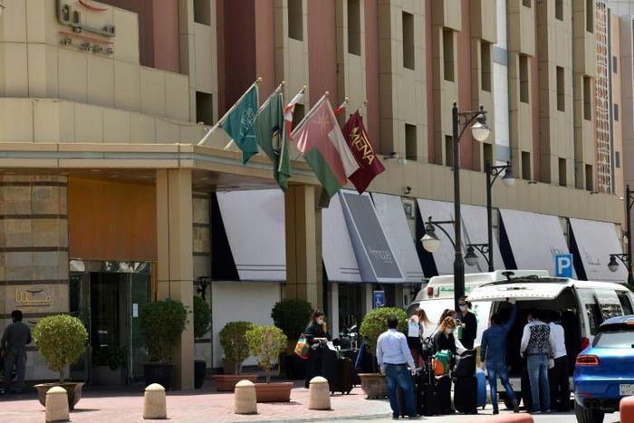 Mask-clad guests depart a hotel in the Saudi capital Riyadh, where hotels have been used to quarantine people to combat the spread of COVID-19