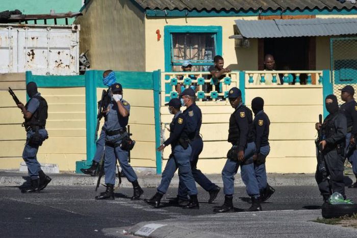 South African police patrol the street during clashes with residents (not visible) of Tafelsig, an impoverished suburb in Mitchells Plain, near Cape Town, on April 14, 2020, after some people in the community did not receive food parcels
