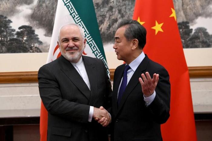 China's Foreign Minister Wang Yi shakes hands with his Iranian counterpart Mohammad Javad Zarif during their meeting in Beijing in December 2019