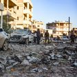 Damaged cars line a street following an air strike in Maarat Misrin on Tuesday