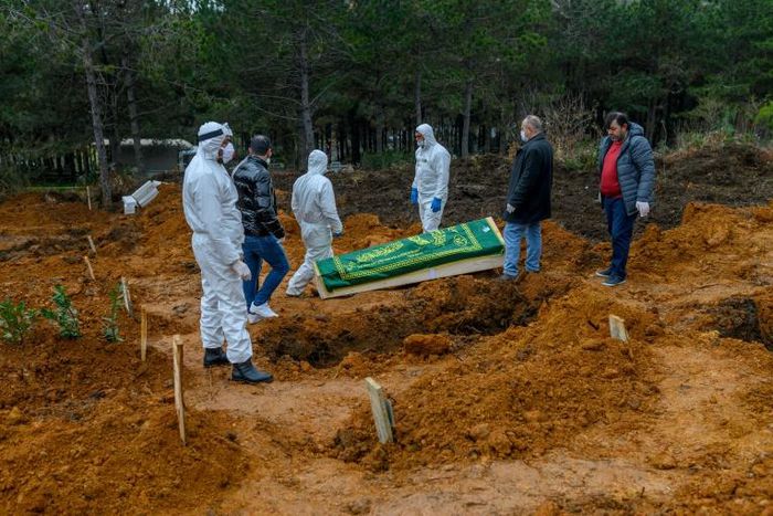 Officers and relatives prepare to bury a person who died from the coronavirus in Istanbul on March 27, at a cemetery opened by the government for victims of the COVID-19 pandemic