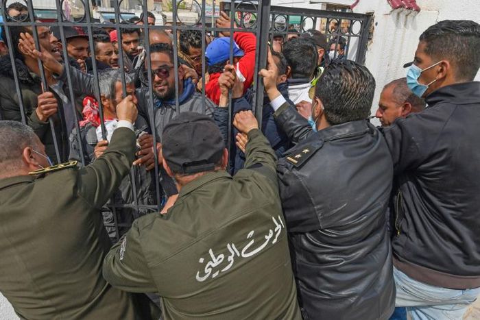 Tunisians angered by a coronavirus lockdown gather outside a government office on the outskirts of the capital
