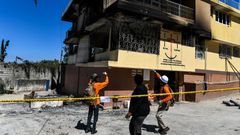 Firefighters speak to a local judge (C) as they point at the Orphanage of the Church of Bible Understanding where a fire broke out the previous night in the Kenscoff area outside of Port-au-Prince February 14, 2020