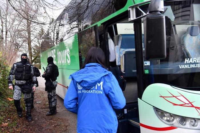 Riot police officers stand guard by a bus carrying illegal migrants following the evacuation of the makeshift camp Vucjak on the outskirts of Northern-Bosnian town of Bihac, on December 10, 2019
