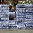 A woman wearing a protective face mask walks past stacks of toilet paper for sale in the Tsuen Wan district of Hong Kong