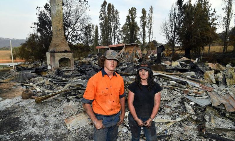 Brother and sisters Jesse and Kiahan Bellchambers stand in front of the charred ruins of their home in Batlow, in Australia's New South Wales state