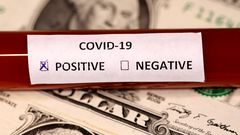 FILE PHOTO: A test tube labelled with the coronavirus is placed on U.S. dollar banknotes, in this illustration taken on March 1, 2020. REUTERS/Dado Ruvic