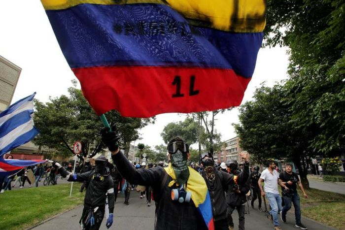 Protestors with their faces covered wave flags during a demonstration against the government of Colombia’s President Ivan Duque in Bogota