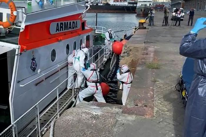 Medics help a sick passenger from an Australian liner off a Uruguay navy launch in Montevideo, on April 3, 2020