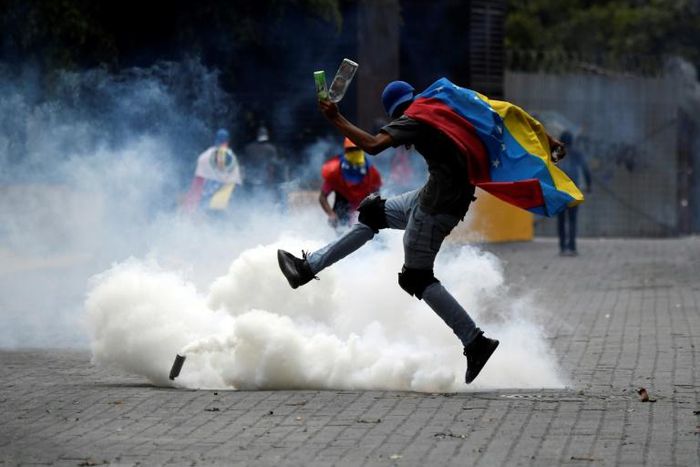 A protester kicks back a tear gas canister fired by security forces on opposition marchers in Caracas
