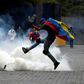 A protester kicks back a tear gas canister fired by security forces on opposition marchers in Caracas