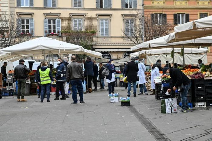 A municipal policeman checks people are keeping their distance at the fruit and vegetable market in piazza San Cosimato, in the Rome district district of Trastevere