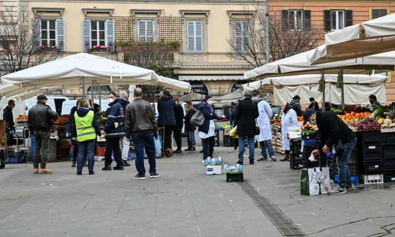 A municipal policeman checks people are keeping their distance at the fruit and vegetable market in piazza San Cosimato, in the Rome district district of Trastevere