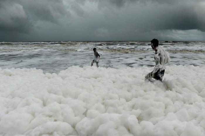 Children have been playing and taking selfies in the clouds of white suds on Marina Beach, even though they give off an acrid smell and fishermen have been told not to go into the sea nearby