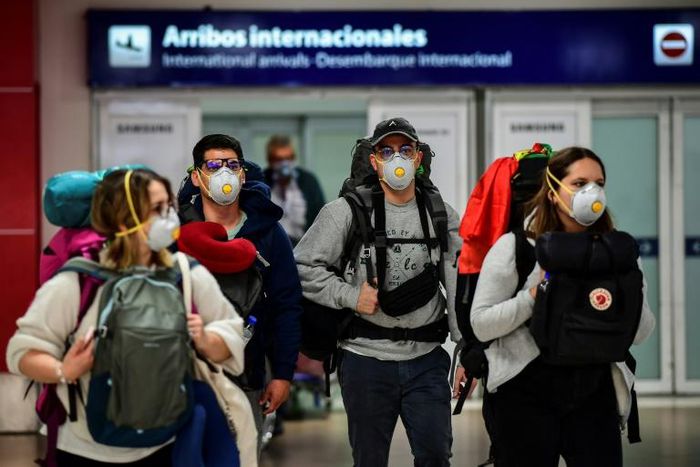Passengers wearing face masks arrive at Ezeiza International Airport in Buenos Aires