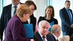 German Chancellor Angela Merkel (L) reaches out to try and shake hands with German Interior Minister Horst Seehofer