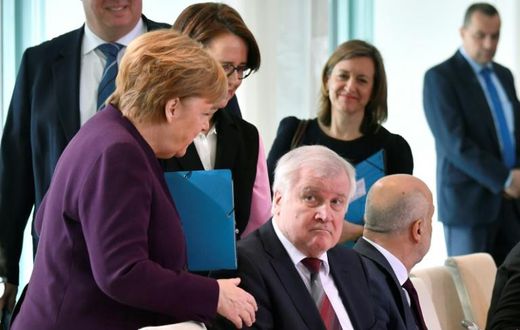 German Chancellor Angela Merkel (L) reaches out to try and shake hands with German Interior Minister Horst Seehofer