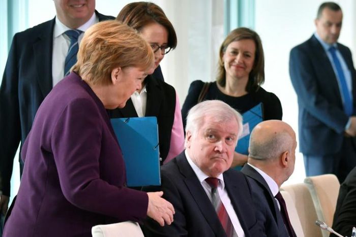 German Chancellor Angela Merkel (L) reaches out to try and shake hands with German Interior Minister Horst Seehofer