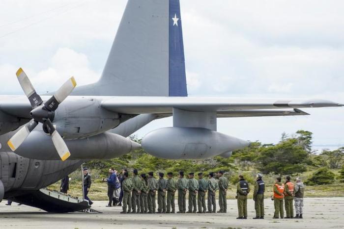 Chilean military personnel stand by an Air Force plane as they wait to unload human remains found during the search for the C-130 Hercules transport plane that crashed in the sea on its way to Antarctica