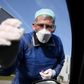 German doctor Michael Grosse takes a sample from a car driver at a drive-through testing point for the coronavirus in Halle, eastern Germany