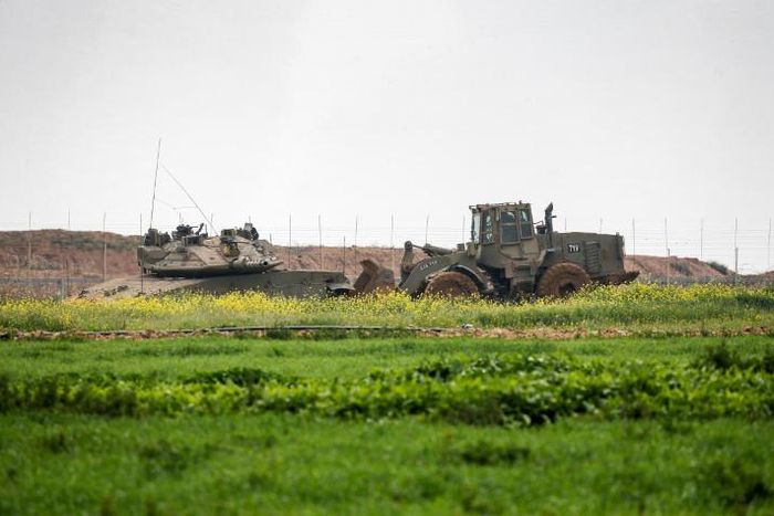 An Israeli tank and a bulldozer are seen along the border fence between Israel and the Gaza Strip where the army says troops shot dead a Palestinian suspected of placing a bomb near the barrier