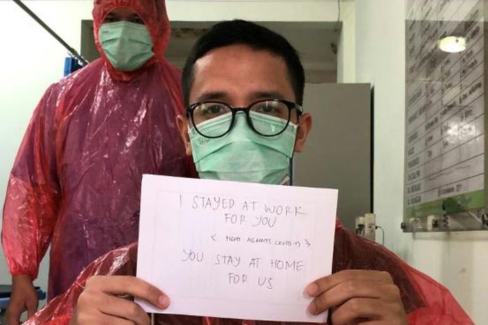 Doctor Muhammad Farras Hadyan, wearing a raincoat because of a shortage of proper protection gear, poses for a selfie during a break from treating patients with coronavirus, in Jakarta