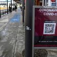 Commuters walk past a sign warning about the COVID-19 at San Ysidro port of entry, in Tijuana, Baja California state, Mexico