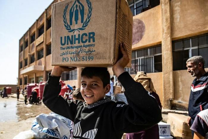Displaced Syrians, who fled their homes in the border town of Ras al-Ain, receive humanitarian aid on October 12, 2019, in the town of Tal Tamr in the countryside of Syria's northeastern Hasakeh province