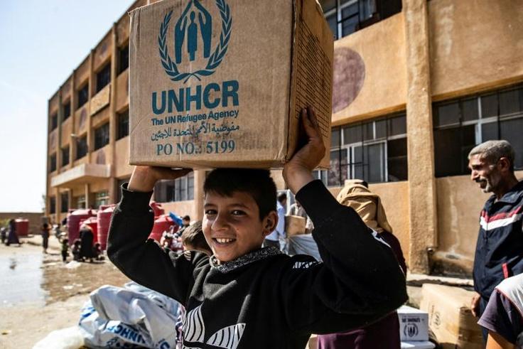 Displaced Syrians, who fled their homes in the border town of Ras al-Ain, receive humanitarian aid on October 12, 2019, in the town of Tal Tamr in the countryside of Syria's northeastern Hasakeh province