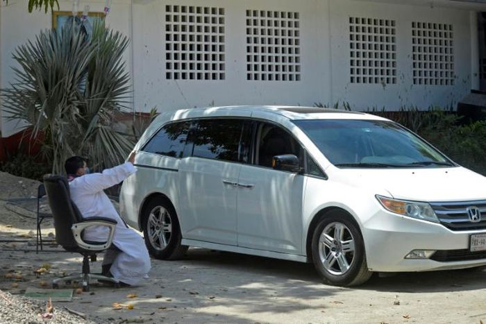 Priest Marco Antonio Galeana hears confession from a penitent in a car in Acapulco, Mexico