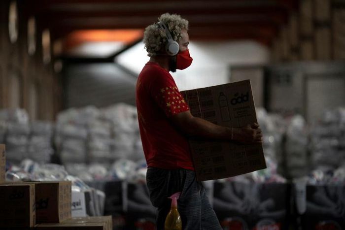 A man carries a box while organizing 40 tons of food and supplies to be delivered to residents of favelas in Rio de Janeiro, Brazil, on April 9, 2020