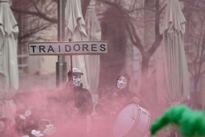 Police wearing Anonymous masks and carrying a sign reading: "traitors" demonstrated outside the parliament in Madrid to demand wage equality with their counterparts in other Spanish regions
