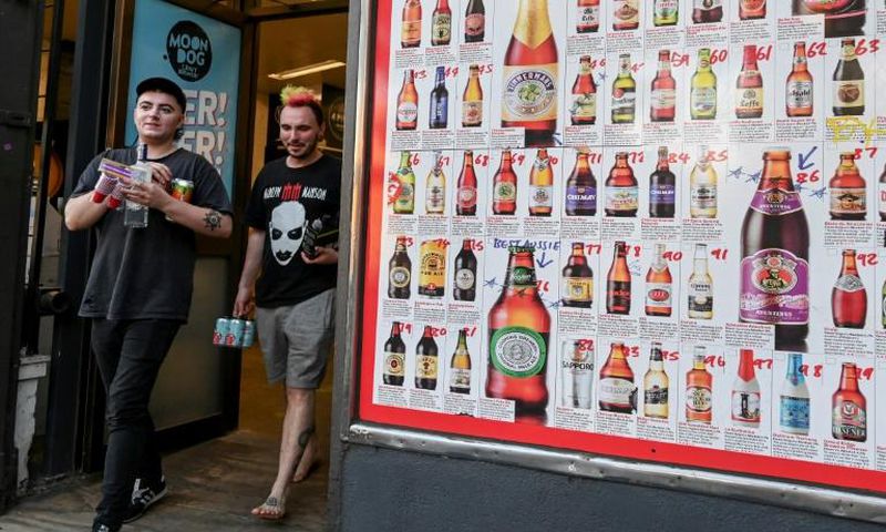 Two men leave a so-called "bottle shop" in Melbourne after major alcohol retailers in Australia agreed to enforce new rules limiting individual purchases