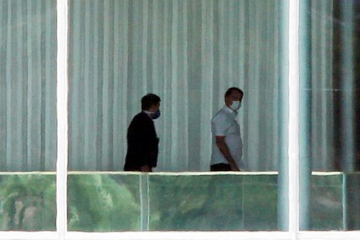 Brazilian President Jair Bolsonaro (R) walks with a consultant inside the Palacio Alvorada, in Brasilia, on March 13, 2020, after testing negative for the new coronavirus