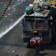 A demonstrator stands in front of police water cannon in Santiago, Chile, which has been rocked by protests