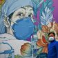 A man wearing a facemask walks in front of a mural at Leishenshan Hospital in Wuhan, China