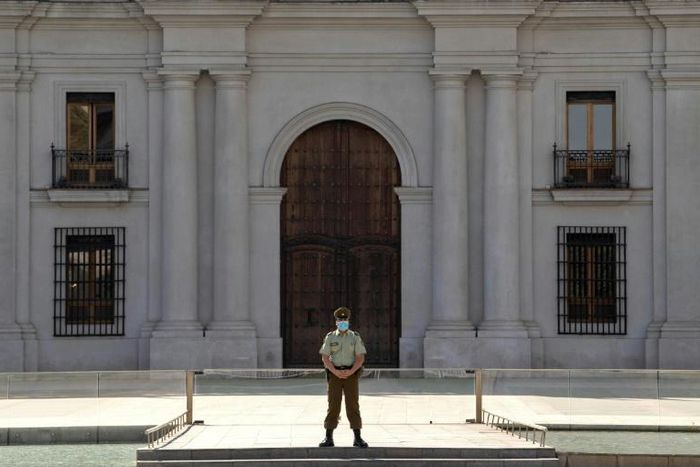 A police officer wears gloves and a face mask as he stands guard outside La Moneda presidential palace in Santiago, Chile, on April 09, 2020