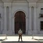 A police officer wears gloves and a face mask as he stands guard outside La Moneda presidential palace in Santiago, Chile, on April 09, 2020