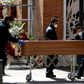 Mortuary employees wearing face masks wheel a coffin into the crematorium at  La Almudena cemetery in Madrid on Tuesday