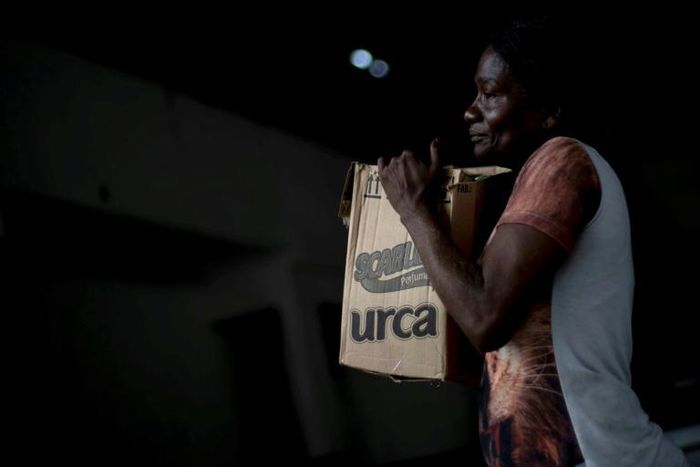 A woman in Rio de Janeiro's City of God favela carries a box with donations of basic food supplies distributed by an NGO to people suffering economic hardship during the novel coronavirus in Brazil