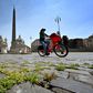 Grass grows between cobblestones as a woman rides a bicycle across Piazza del Popolo on April 24, 2020 in Rome, during the country's lockdown aimed at stopping the spread of the COVID-19 pandemic, caused by the novel coronavirus
