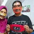 Imama Saroso and his wife Faizah Badaruddin, who are hearing and speech-impaired, pose with homemade face masks which enables people with disabilities to read lips
