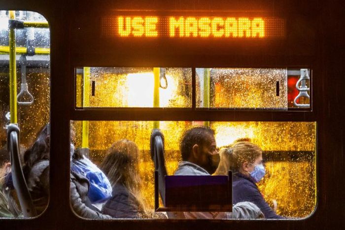 Commuters wearing face masks travel on a public bus with an electronic sign reading "Wear a face mask", in Curitiba, Brazil on May 22, 2020