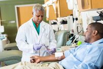 Phlebotomist checking line whle patient donates blood in hospital