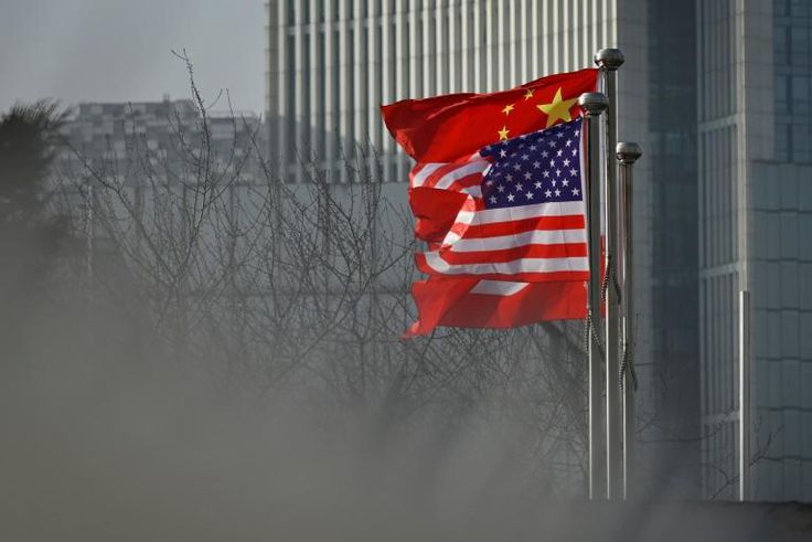 Chinese and US national flags flutter at the entrance of an office in Beijing in January 2020