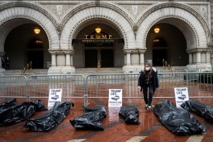 Participants in a "People's Motorcade" stop at the Trump International Hotel to deliver fake body bags during a protest against the administration's response to the COVID-19 pandemic in Washington, DC