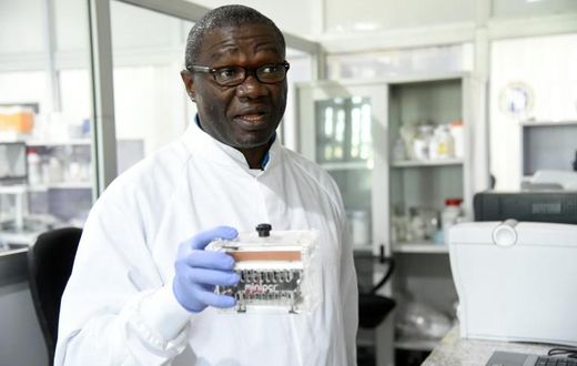 Molecular biologist Christian Happi, head of the ACEGID genomics lab, holds a thermal cycler, which amplifies genetic segments of the virus